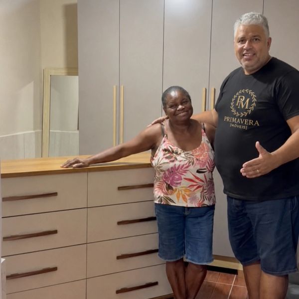 Duas pessoas sorridentes ao lado de um armário.