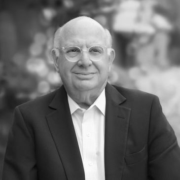 Portrait of an elderly man in glasses and suit jacket.