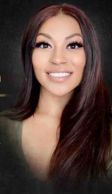 Smiling woman with long hair and makeup.