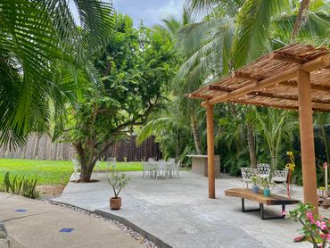 Área de jardín con hermoso árbol y mobiliario de uso común; cuenta con asador y un pergolado. 