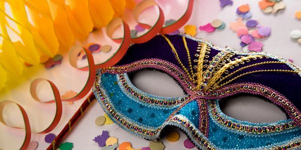 Colorful masquerade mask with confetti and streamers for celebration.