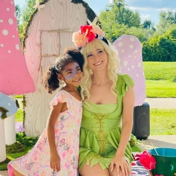 Woman in a green fairy costume with a girl in a floral dress.