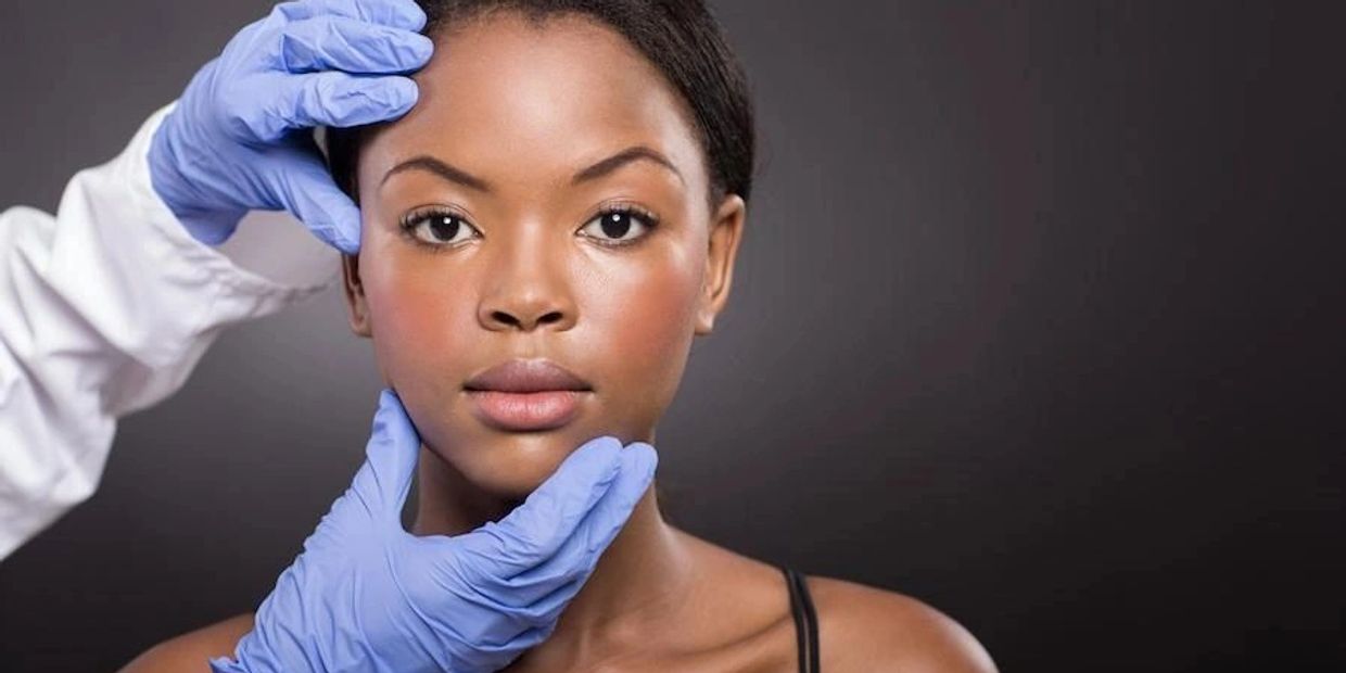 Gloved hands examining a woman's face against a dark background.