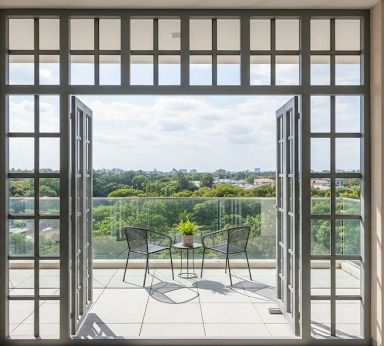 Open balcony doors with chairs and a scenic view.
