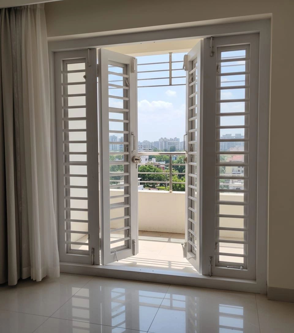 Open white balcony doors with city view.