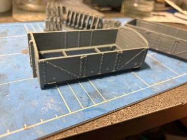 Model of a riveted metal container on a work table.