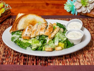Grilled chicken Caesar salad with toast and dressing.