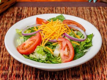 Fresh salad with tomatoes, lettuce, onions, and shredded cheese.