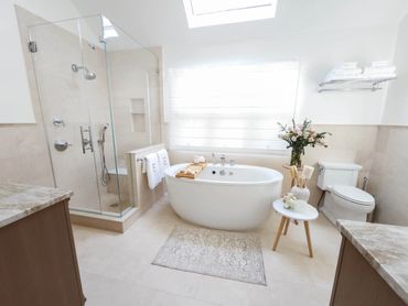 Bright modern bathroom with freestanding tub and glass shower.
