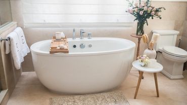 Elegant white freestanding bathtub in a cozy, well-lit bathroom.