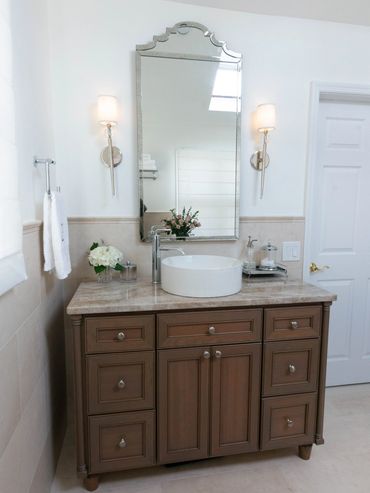 Elegant bathroom vanity with round sink and decorative mirror.