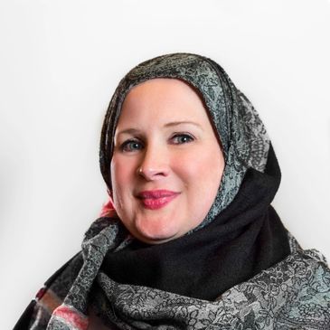 Smiling woman wearing a patterned hijab against a white background.