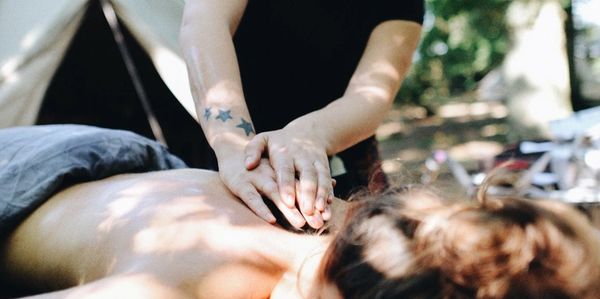 Woman having  a hot stone massage therapy treatment outside a woodland yurt. 