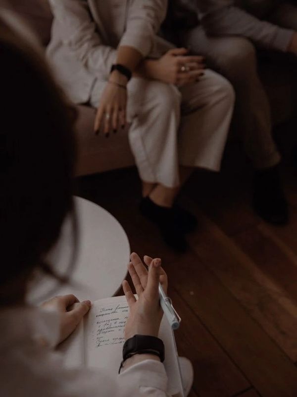 Person taking notes during a conversation in a cozy setting.