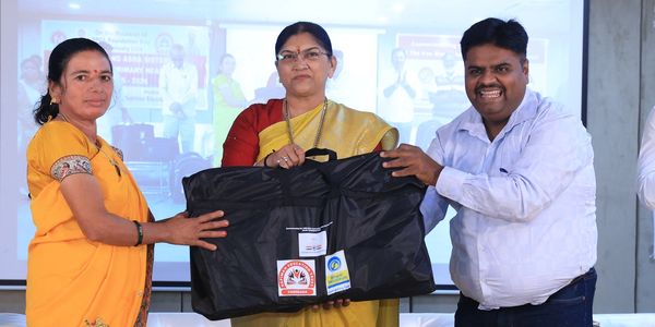 Three people holding a large black bag, posing for a photo.