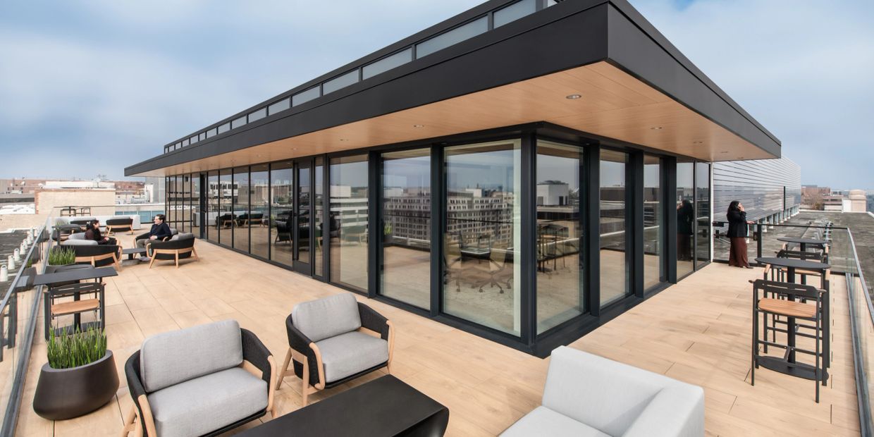 Modern rooftop terrace with seating and glass walls overlooking the cityscape.