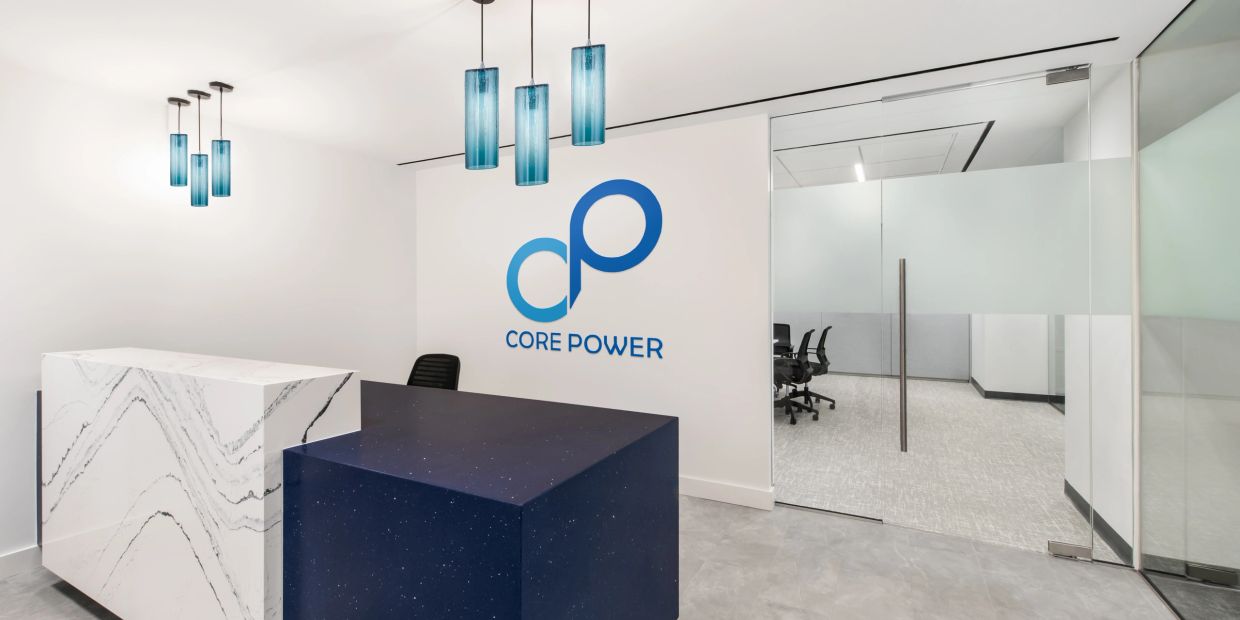 Modern office reception with blue and white desks and glass meeting room.