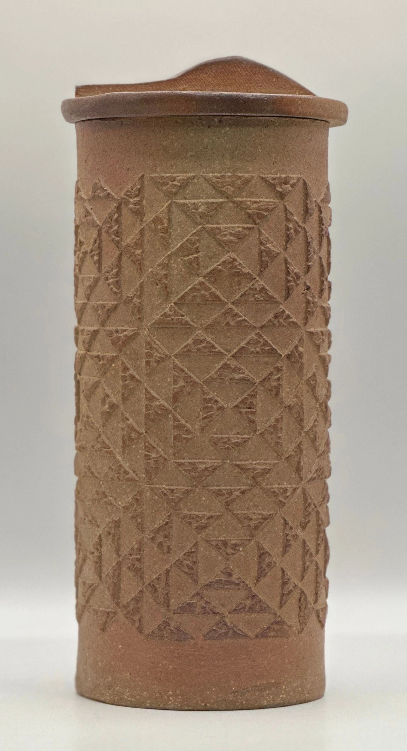 Ancient ceramic container with geometric patterns and lid.