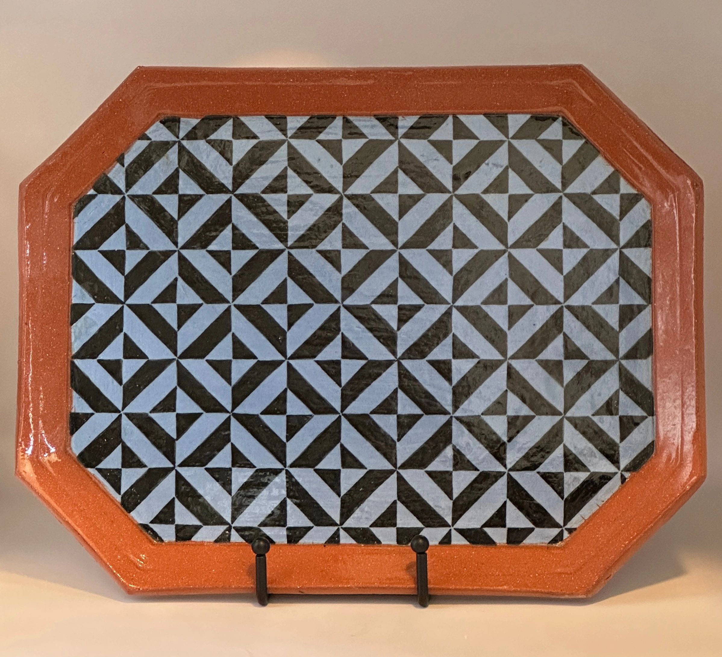 Decorative ceramic tray with geometric black and white pattern and orange border.