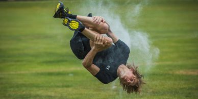 A person performing a mid-air flip with chalk dust around them.