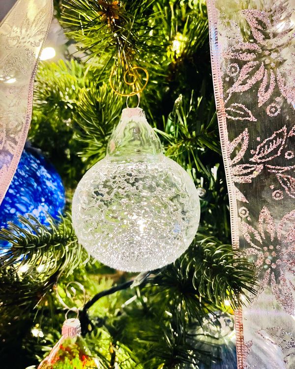 Clear glass and frit Christmas bulb on a tree