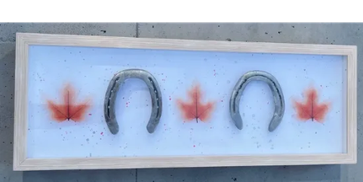 Horseshoes and red glass maple leaves in a frame