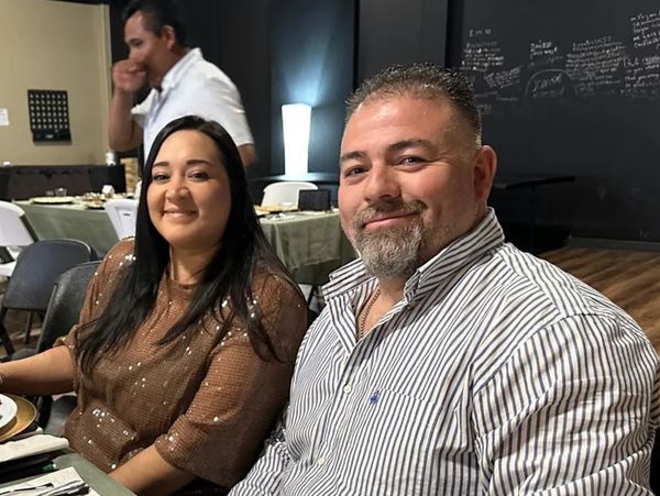 Pareja sonriente en una cena formal con libros en la mesa.