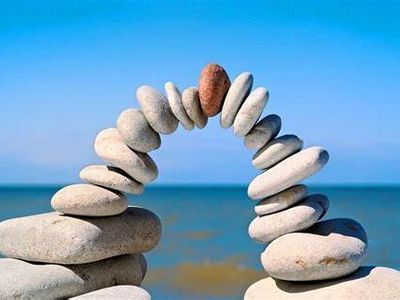Balanced stones forming an arch by the sea.