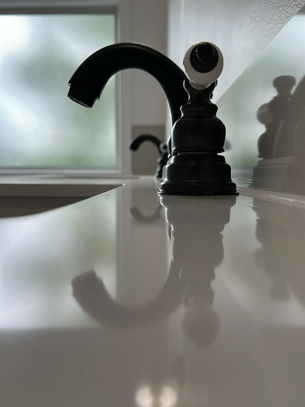 granite countertop with 2 black bathroom vanity faucets