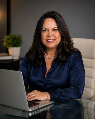 Professional woman sitting at desk with laptop, smiling.