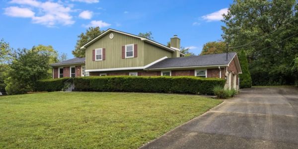 A suburban house with green siding and a large driveway.