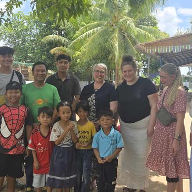 Group of people smiling outdoors with palm trees.
