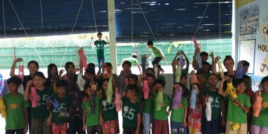 Group of children posing with hands raised indoors.