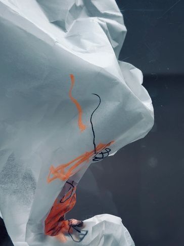 Close-up of crumpled white paper with orange and black scribbles.
