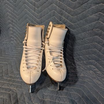 A pair of white figure skates neatly placed together.