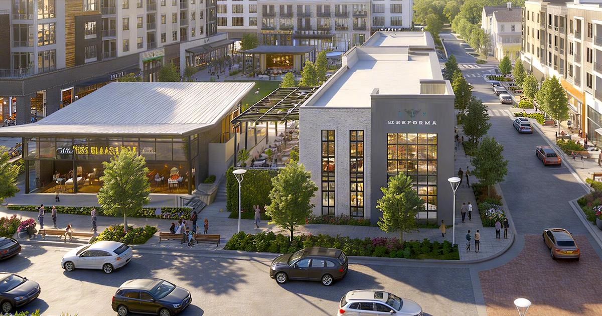 Modern outdoor shopping and dining area with people and cars.