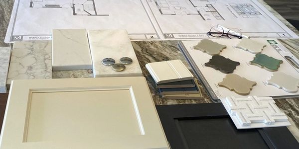 Interior design samples with tiles, cabinet doors, and floor plans on a table.