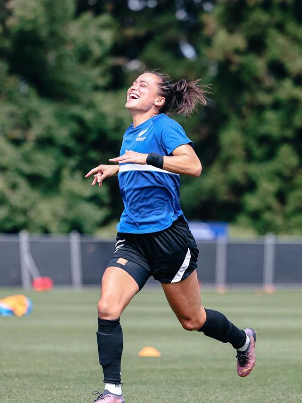 Female soccer player joyfully running on field.