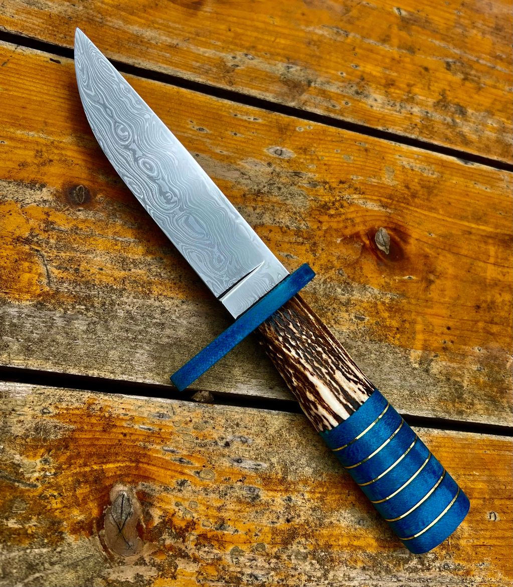 O1, 4150, and L6 Steel. 120 Layer Random Pattern Damascus Belt Knife. Denim Micarta, Brass, and Elk.