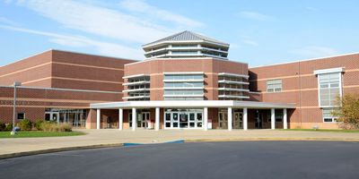 Modern brick school building with a large entrance and clear sky.