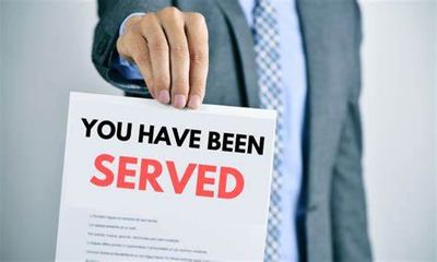 Person holding a 'You have been served' legal document.