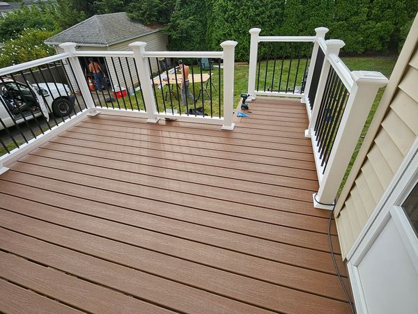 A large, clean wooden deck with white railings leading to a house.