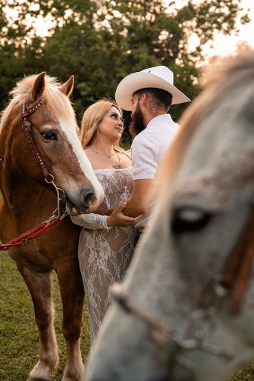 Couple with horses in a serene outdoor setting.