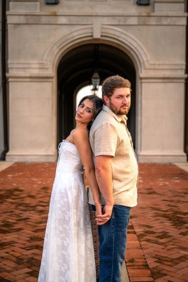 Couple standing back to back holding hands.