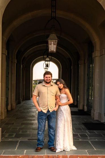 Couple posing under archway at sunset.