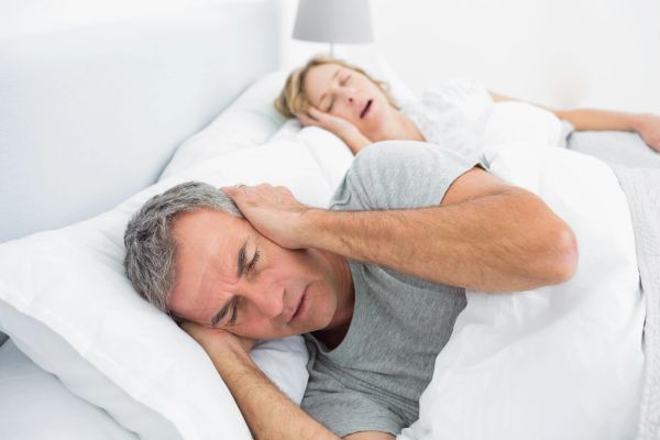 Mann som dekker ørene og kvinne som sover.
