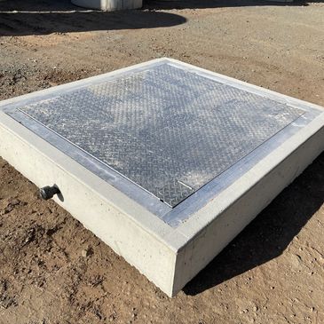 Metal-covered concrete structure on dirt ground.