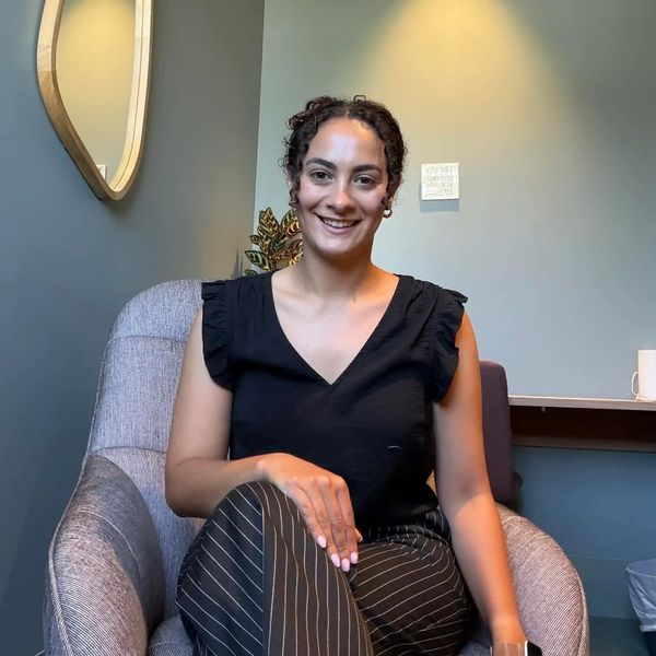 A smiling woman sitting comfortably in a modern chair in a cozy room.