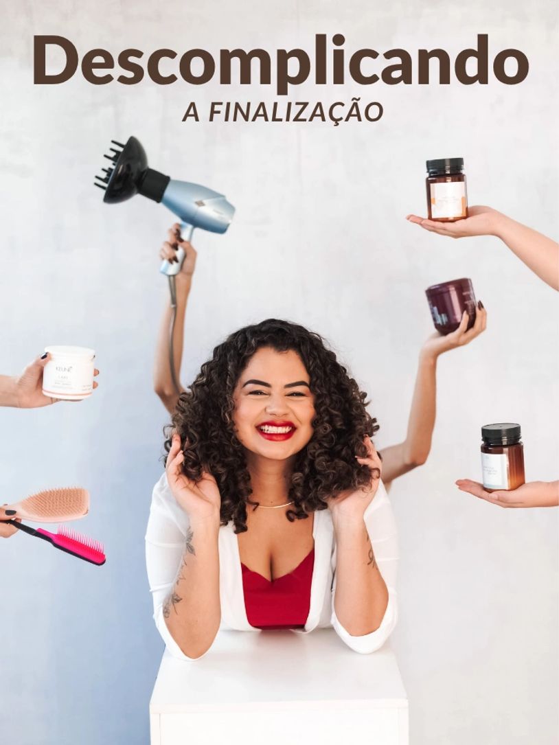 Woman smiling with curly hair surrounded by hair care products and tools.