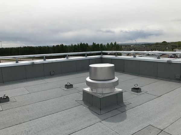 Flat rooftop with ventilation system and cloudy sky.